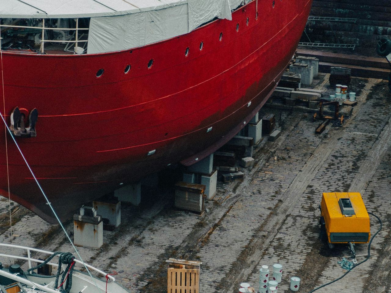 A red-hulled ship under construction in dry dock