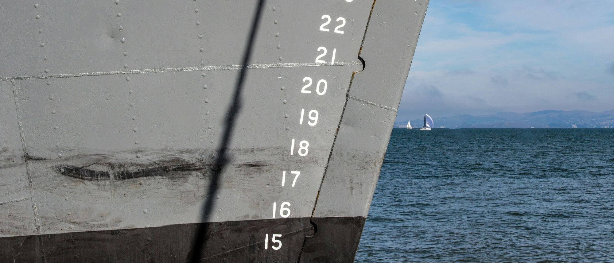 Draft marks and plating on the side of a grey-hulled ship
